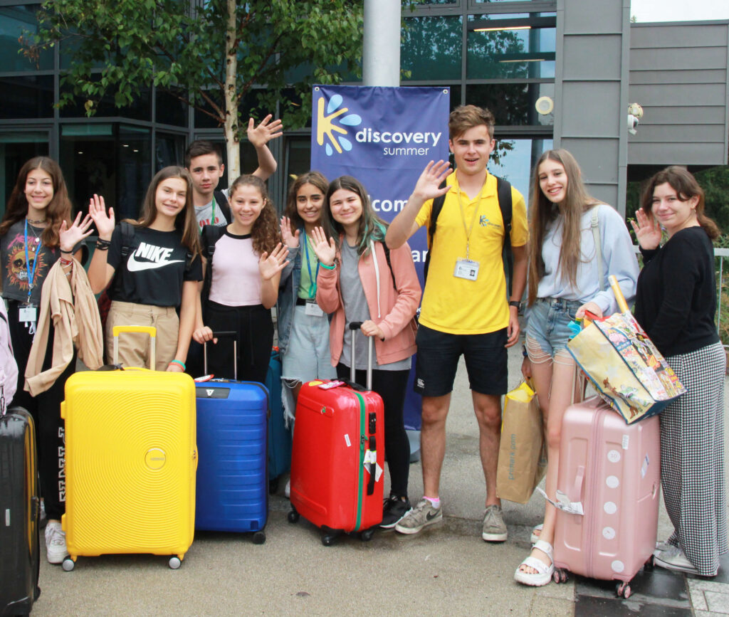 Students waving with their packed suitcases